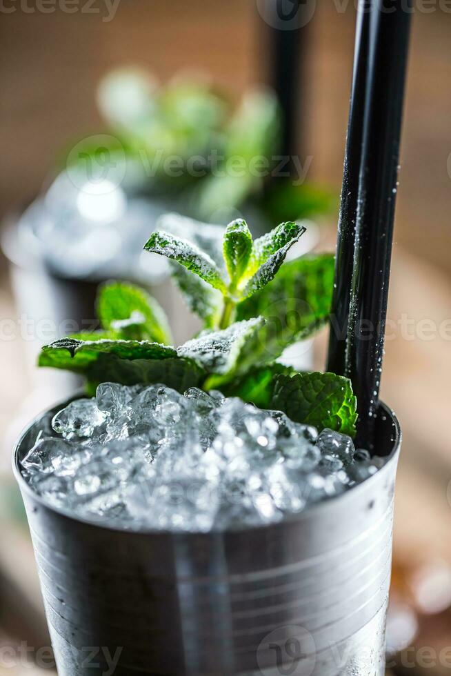 Mint julep cocktail alcoholic drink on wooden board in pub or restaurant photo