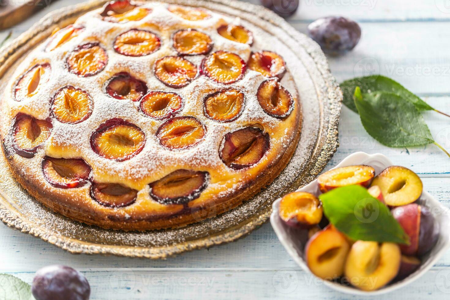 Homemade plum cake in vintage plate on wooden table. Plums pie with sugar powder photo