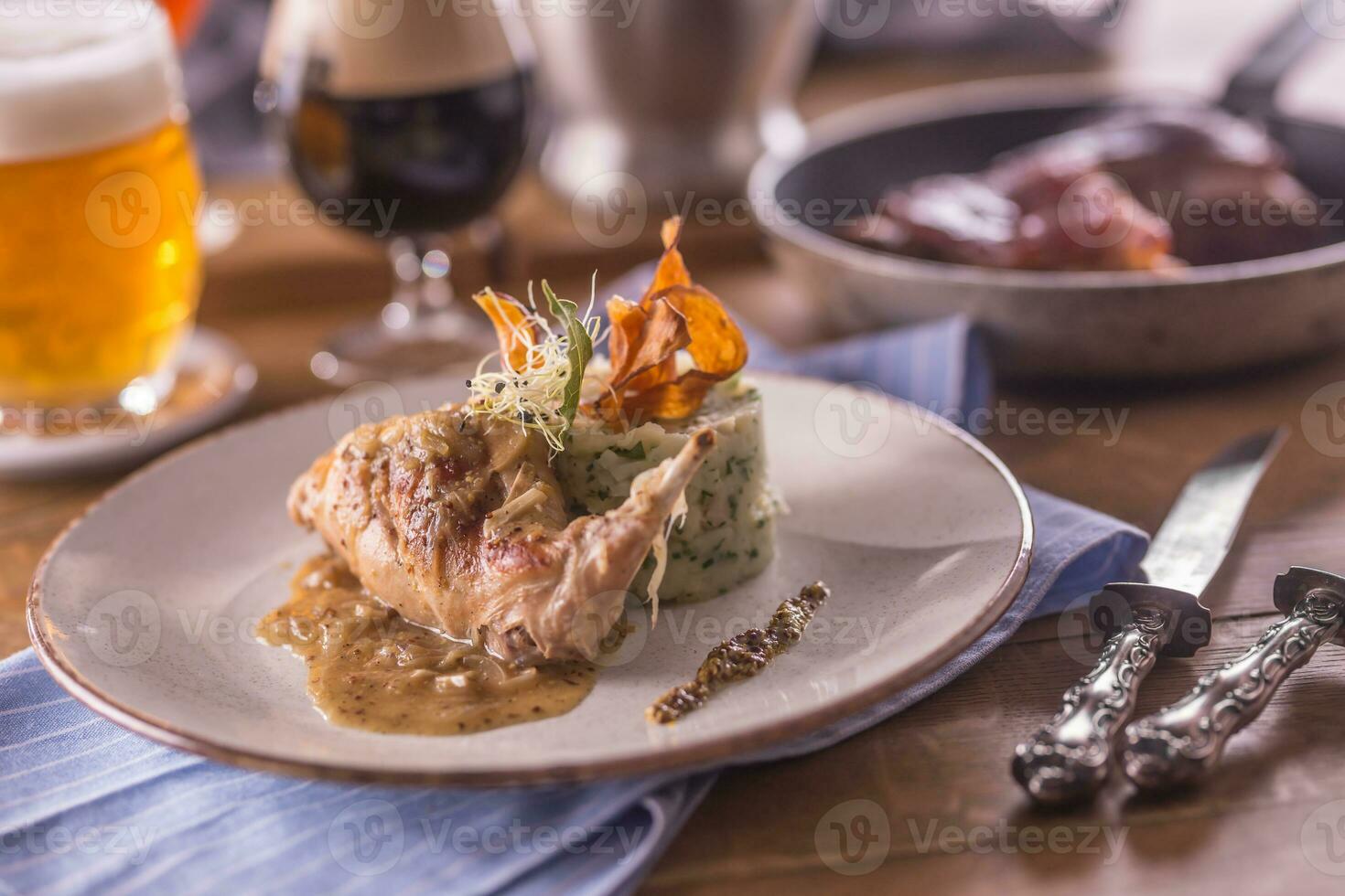 Rabbit leg with mashes potatoes and decoration on plate in restaurant photo