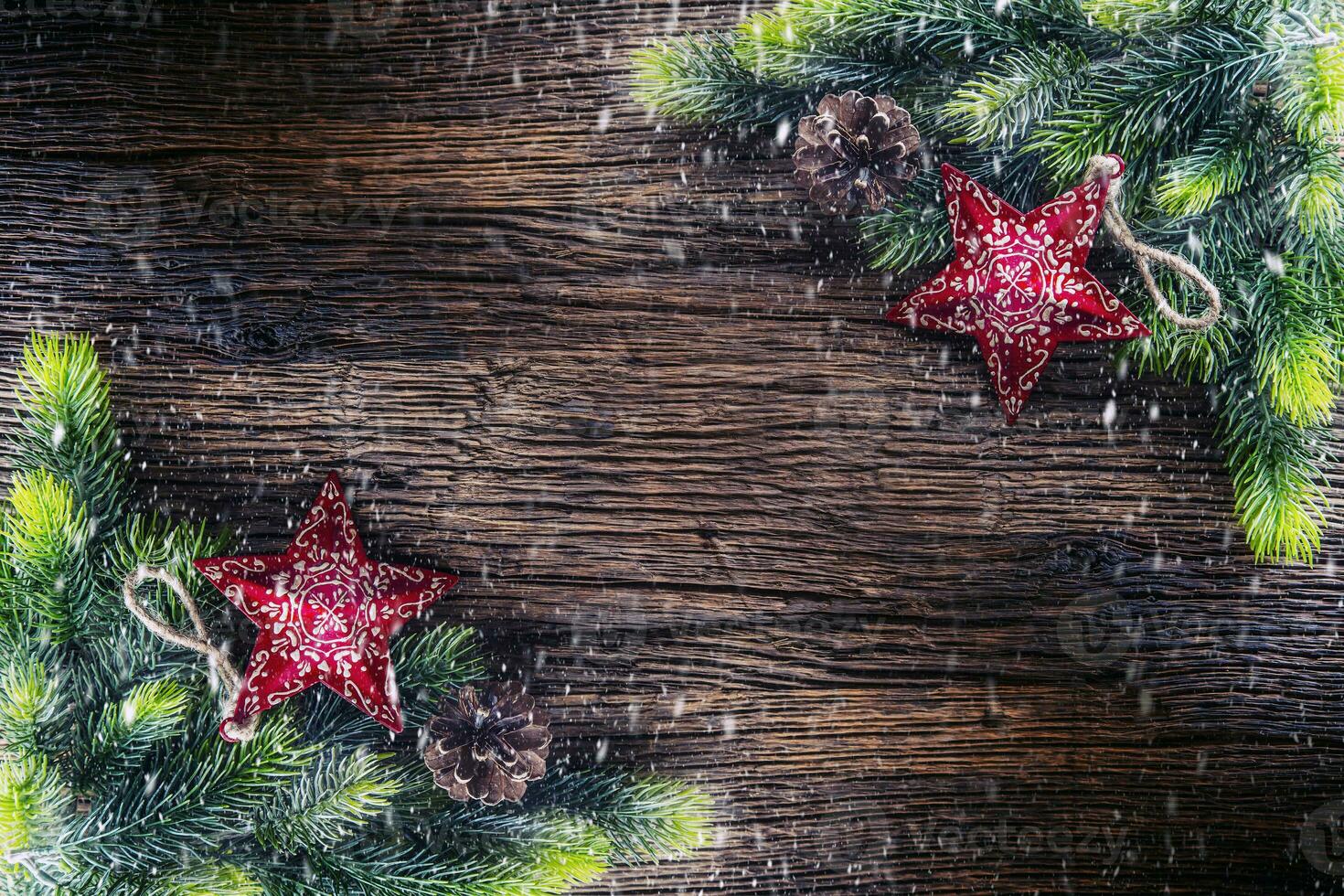Christmas. Christmas fir tree with star and  pine cone on rustic wooden table. Diagonally composition border in snowy atmosphere photo