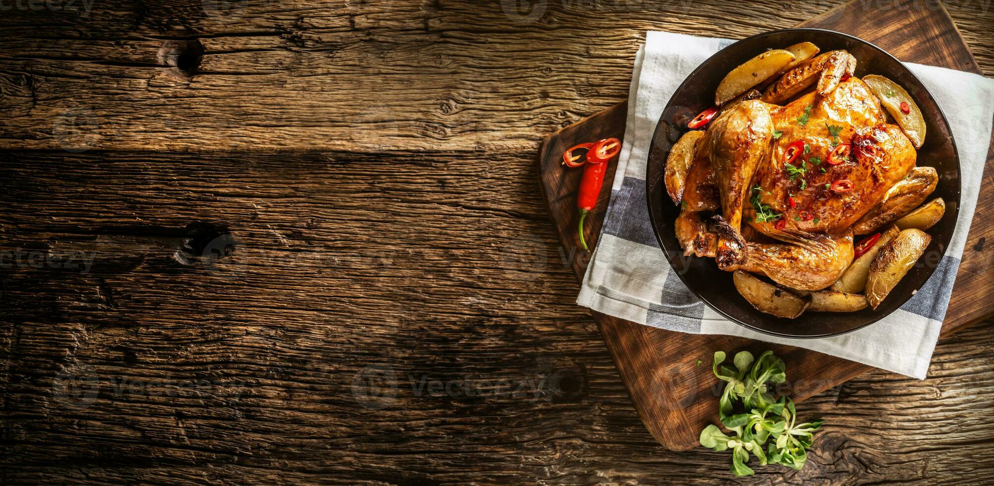 Roasted chicken and american potatoes with chili peppers and herbs - Top of view photo