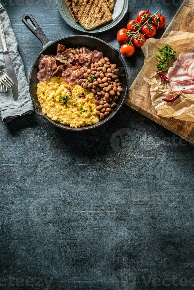 English breakfast scrambled eggs grilled bacon beans and toast bread - Top of view photo