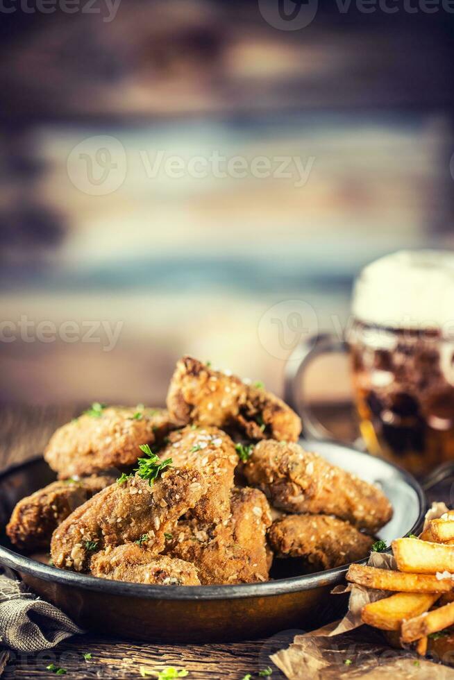 Fried chicken wings fries and draft beer on table. photo