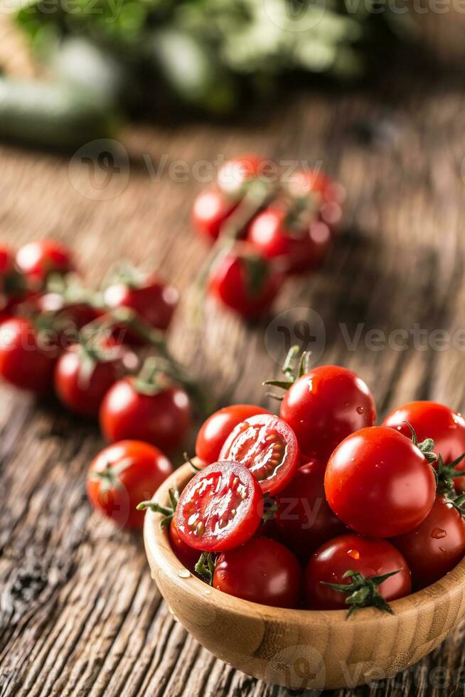 Fresh cherry tomatoes in wooden bowl on old oak table photo