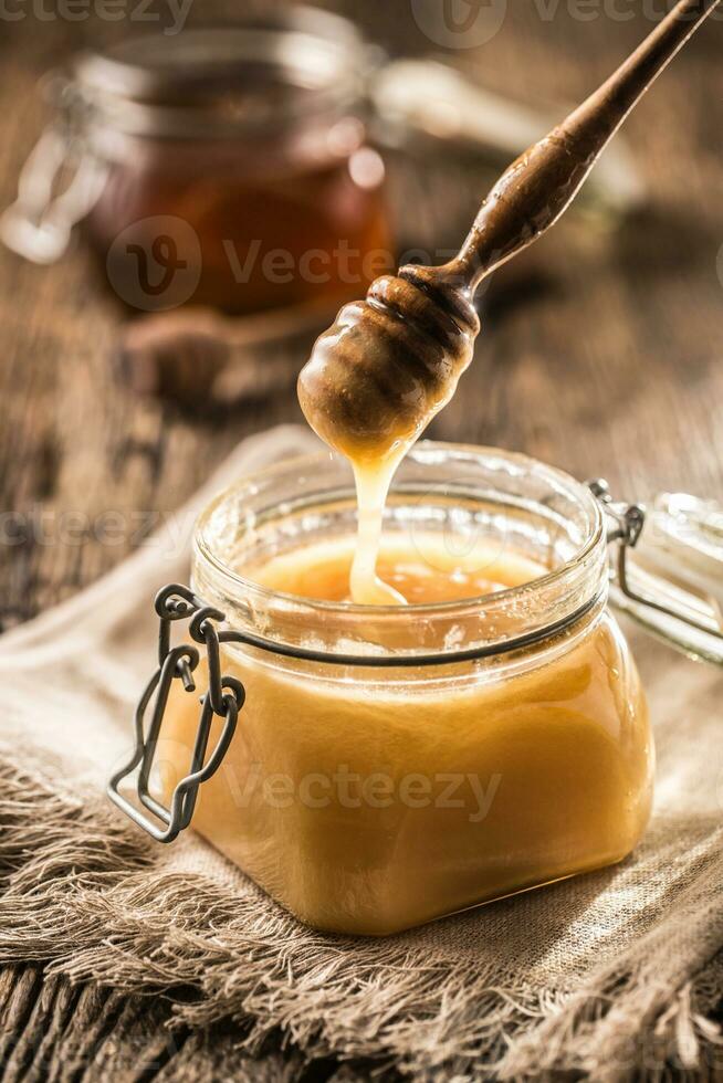 Honey in jars and  dipper on rustic oak table photo