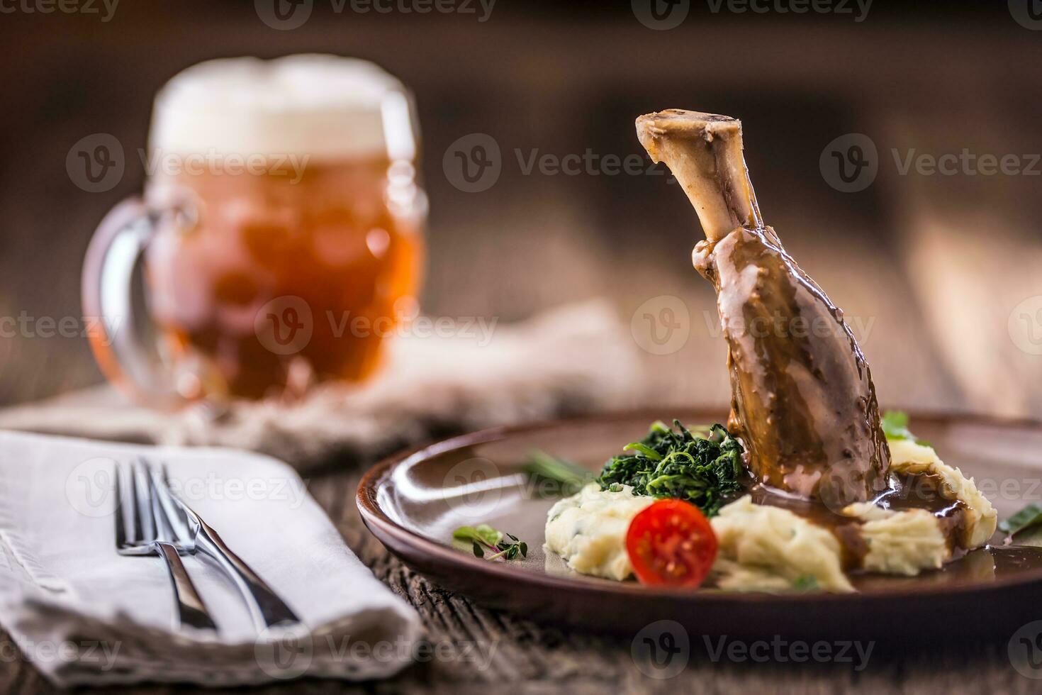 Lamb shank.Confit lamb shank with mashed potatoes spinach and draft beer in pub or restaurant photo