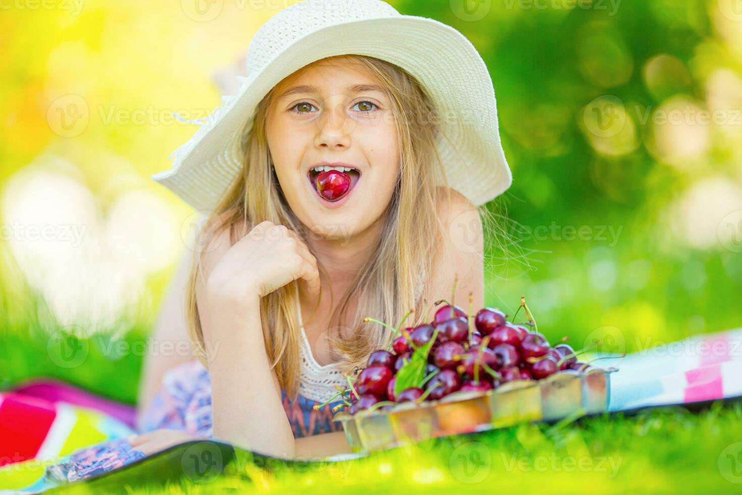 Child with cherries. Little girl with fresh cherries. Portrait of a smiling young girl with bowl full of fresh cherries. photo