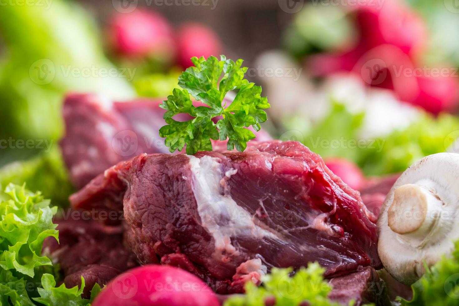 Raw beef meat with fresh vegetable. Sliced beef steak in lettuce salads radishes and mushrooms. photo