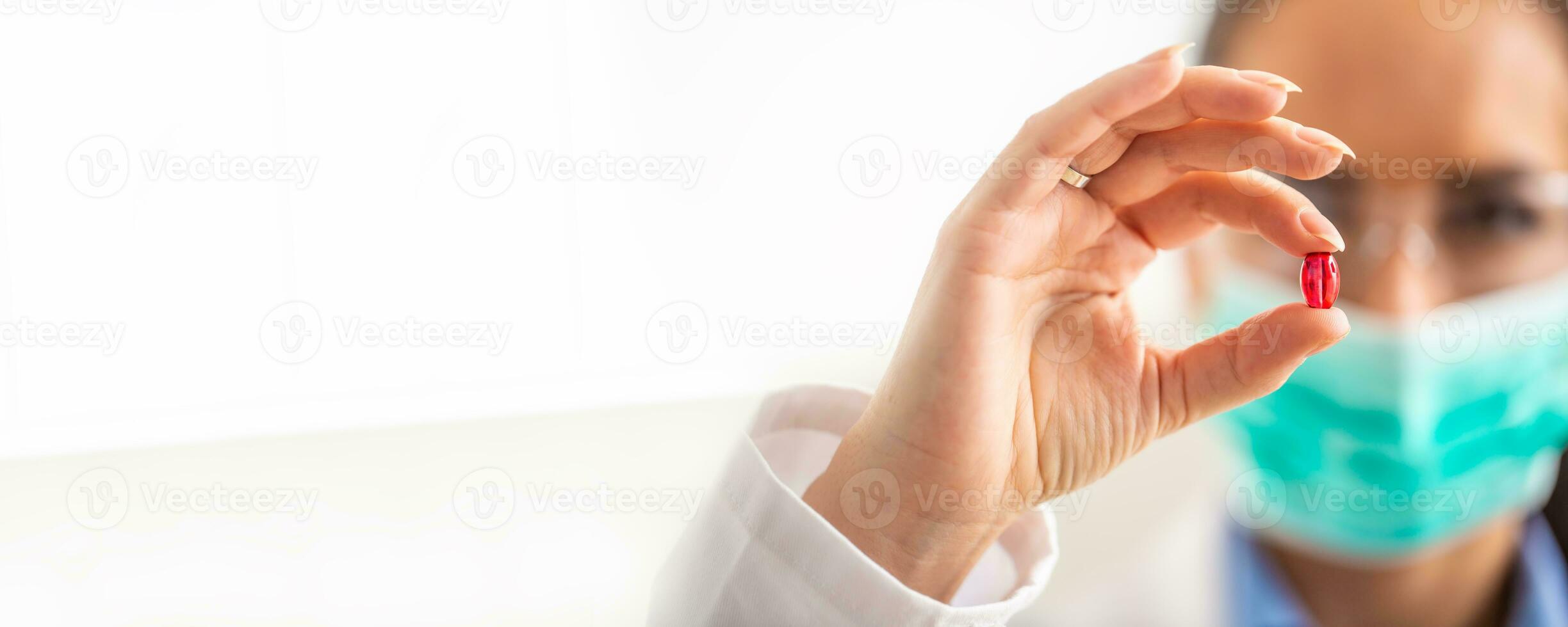 Young female scientist holding a red pill - close-up photo