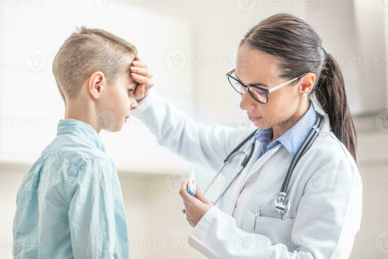 médico mujer es medida el temperatura de joven chico en médico oficina foto