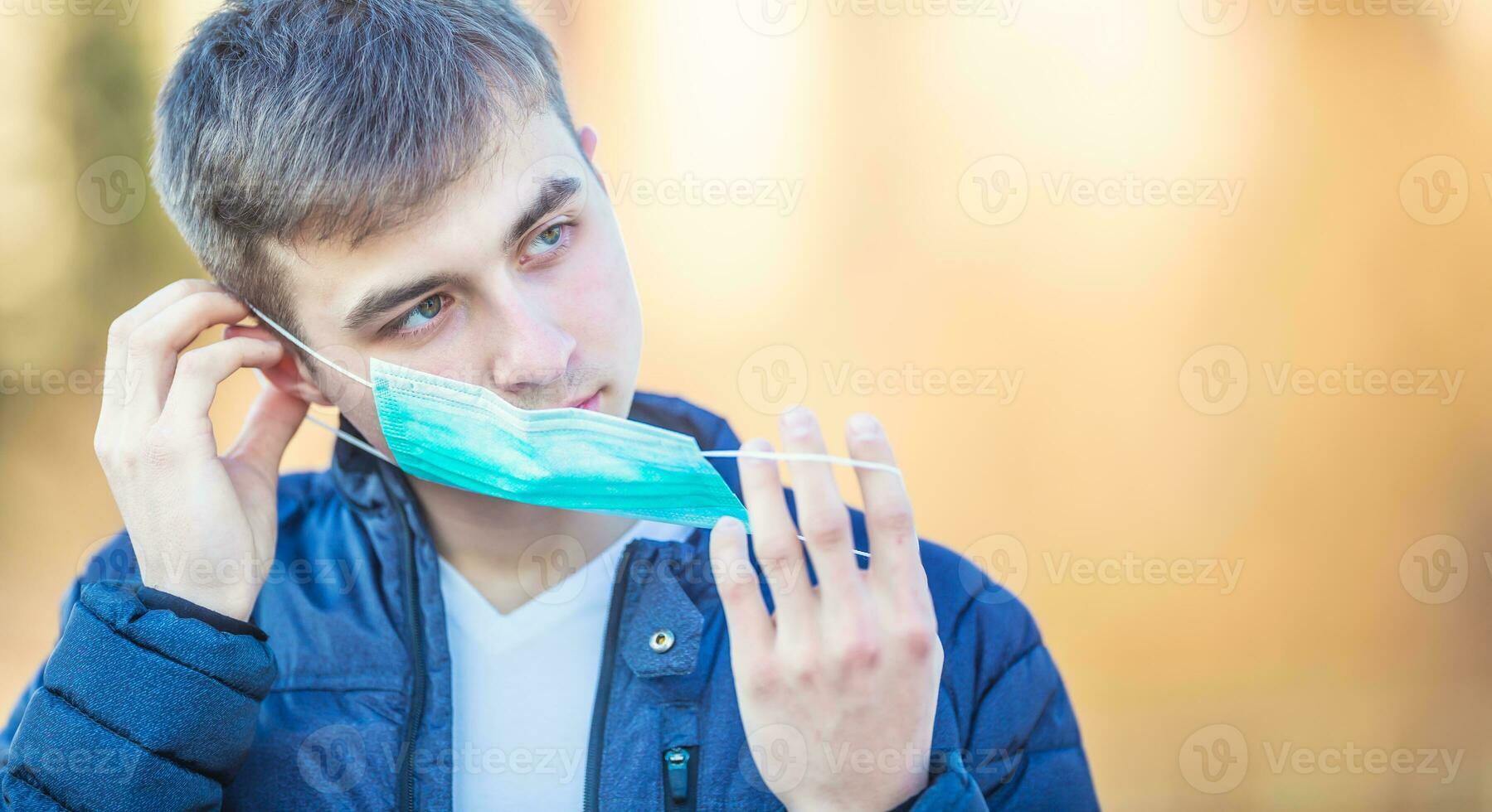 Young man puts protective mask on his face. Protection against virus dust or smog. Coronavirus Covid-19 concept photo