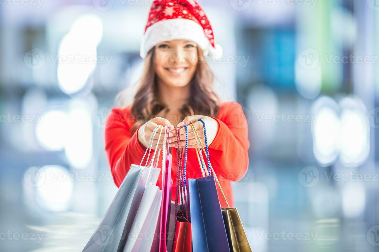 Navidad compras. atractivo contento niña con crédito tarjeta y compras pantalones en Papa Noel sombrero foto