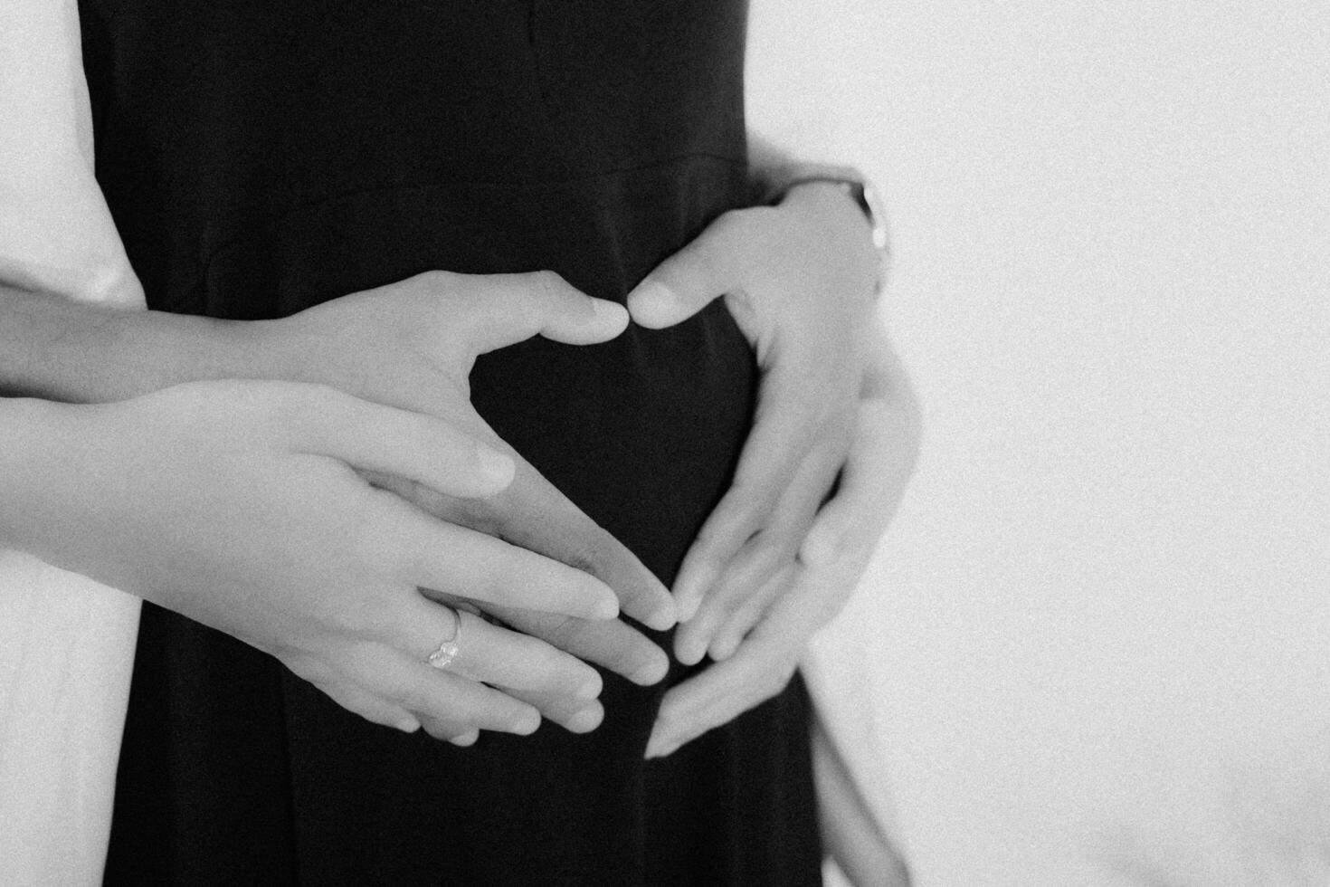 a pregnant woman is holding her belly in a heart shape photo
