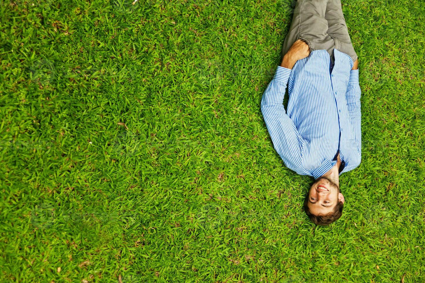 a man laying on the grass with his legs up photo