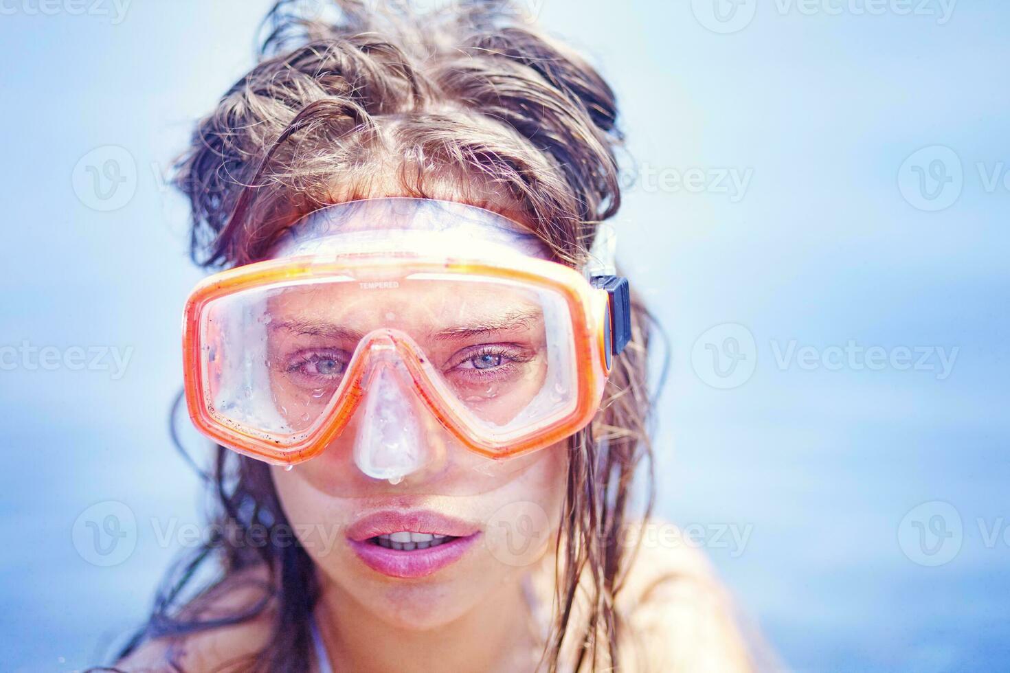 a woman wearing a snorkel and goggles in the ocean photo