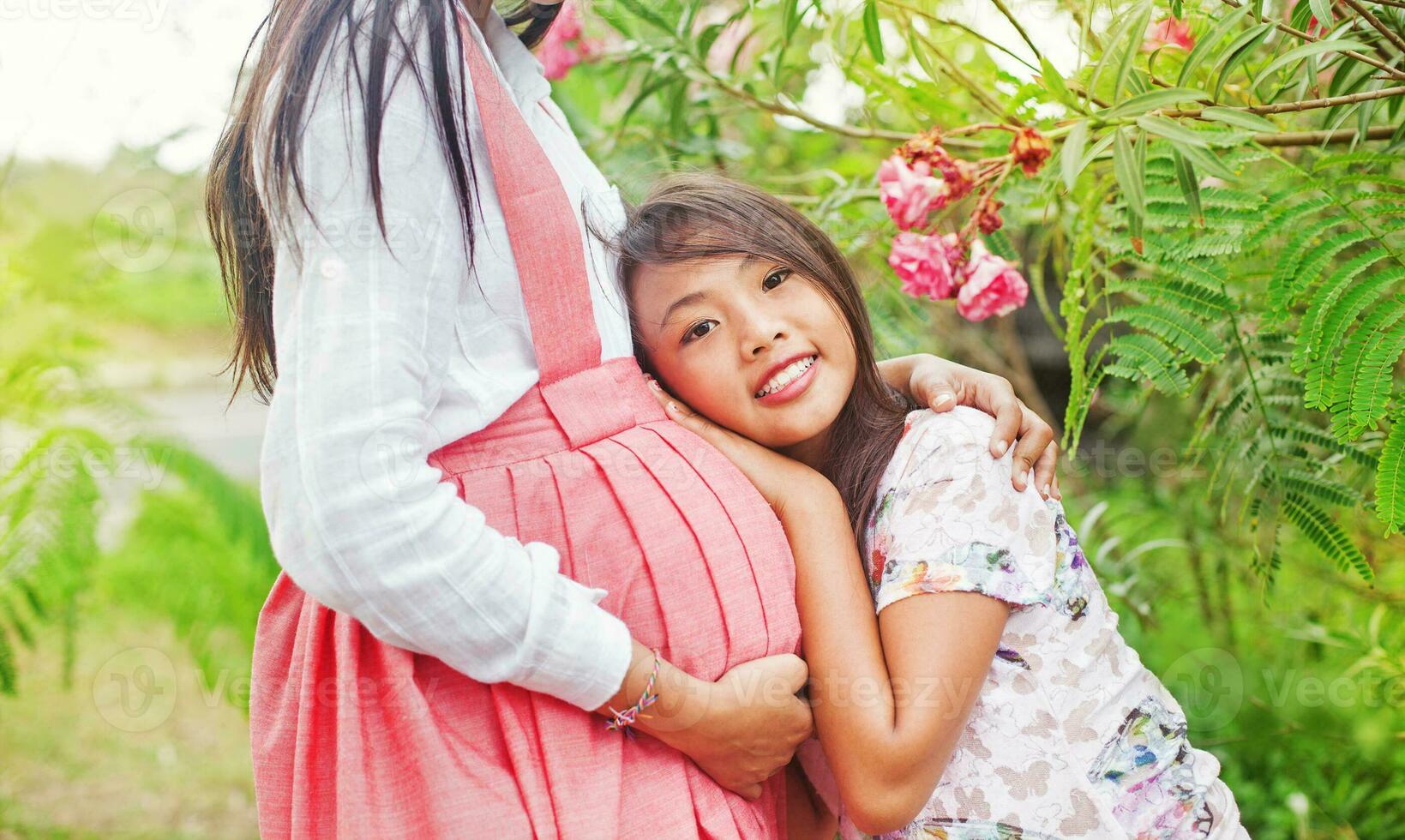 a woman and her daughter are hugging in the grass photo