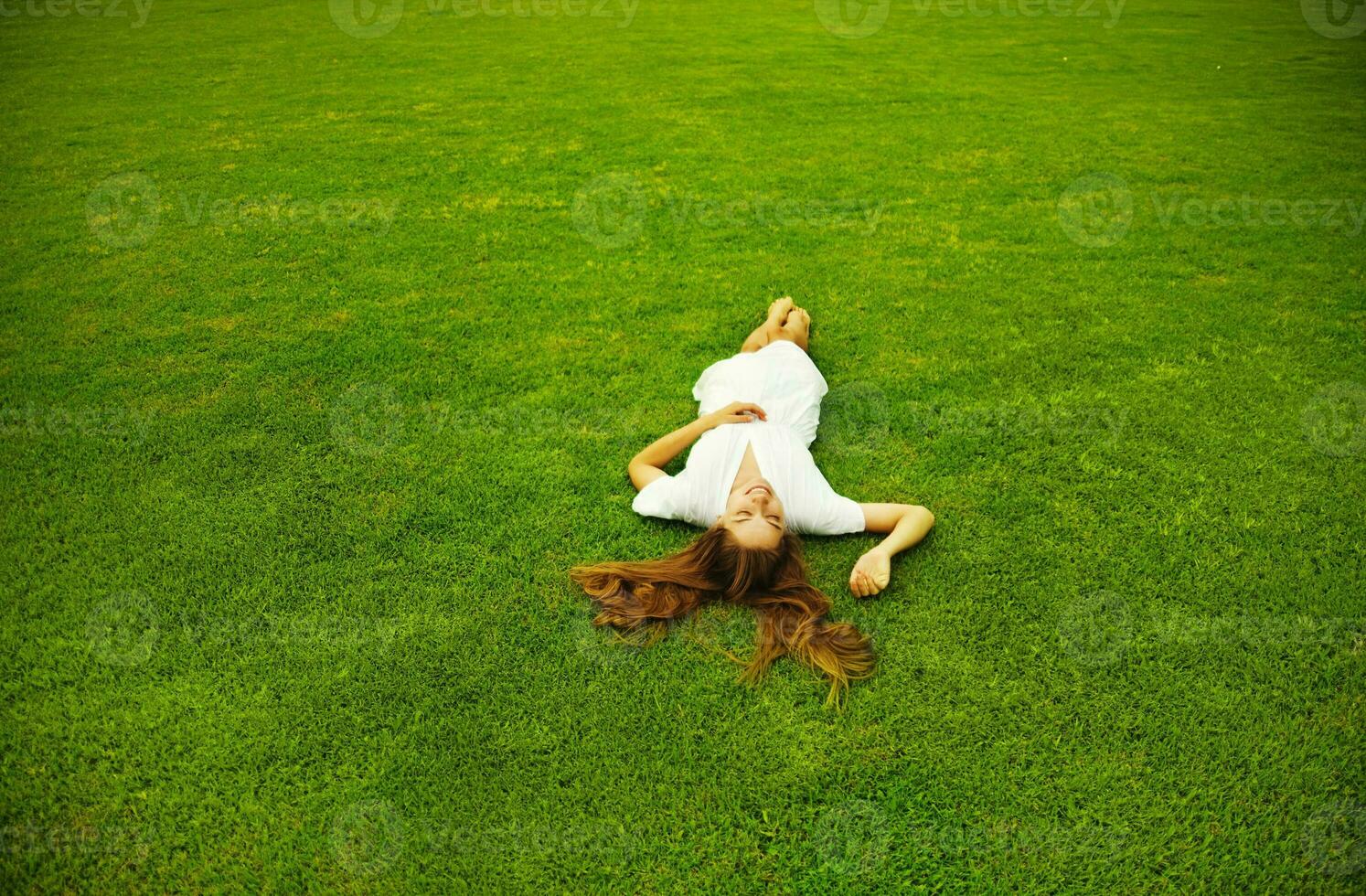 a woman laying on the grass in a field photo
