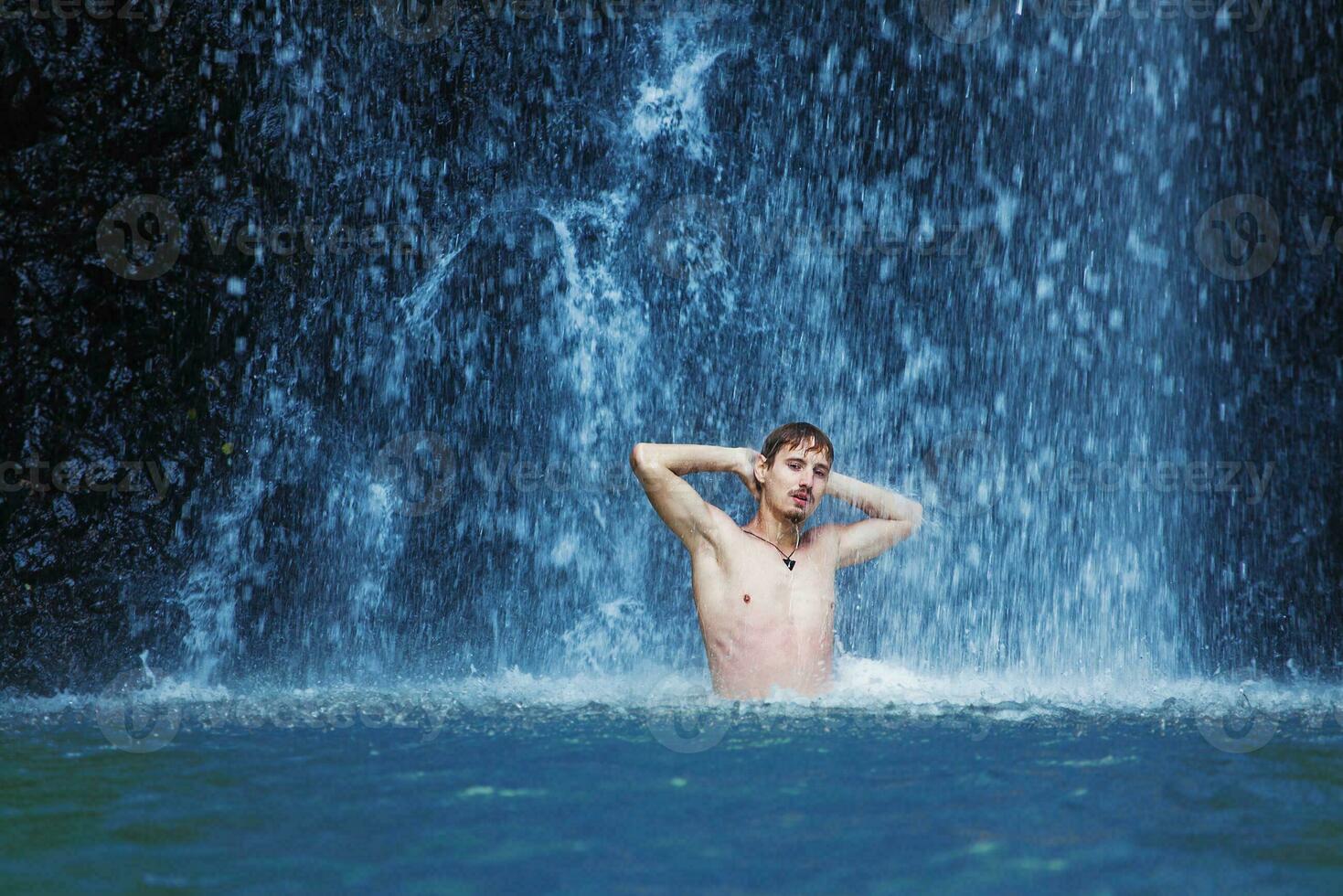 a man standing in front of a waterfall photo