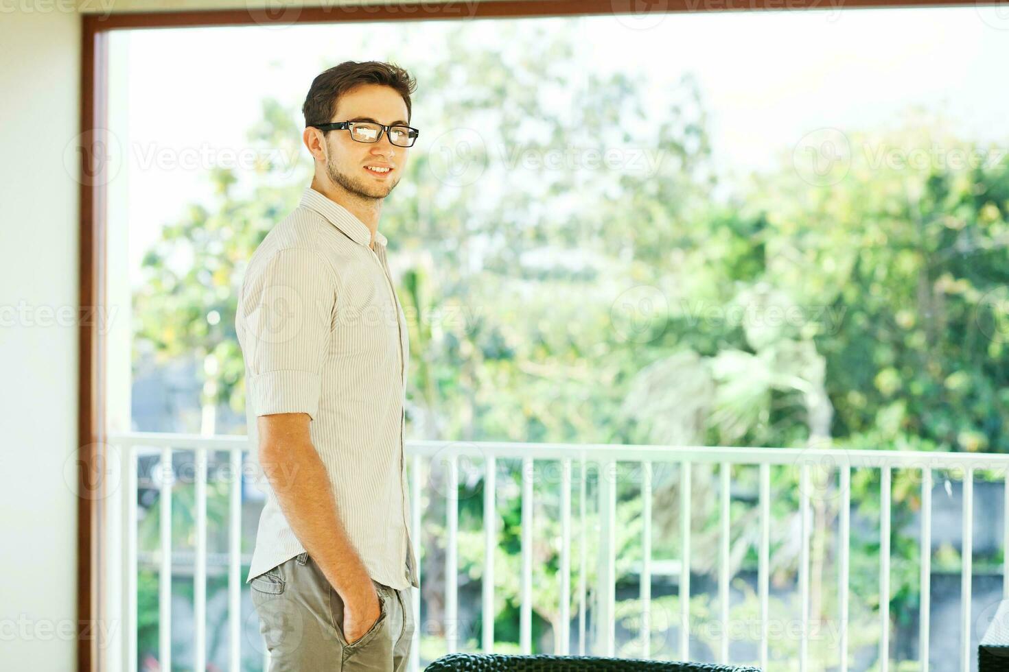 un hombre en lentes en pie en frente de un ventana foto