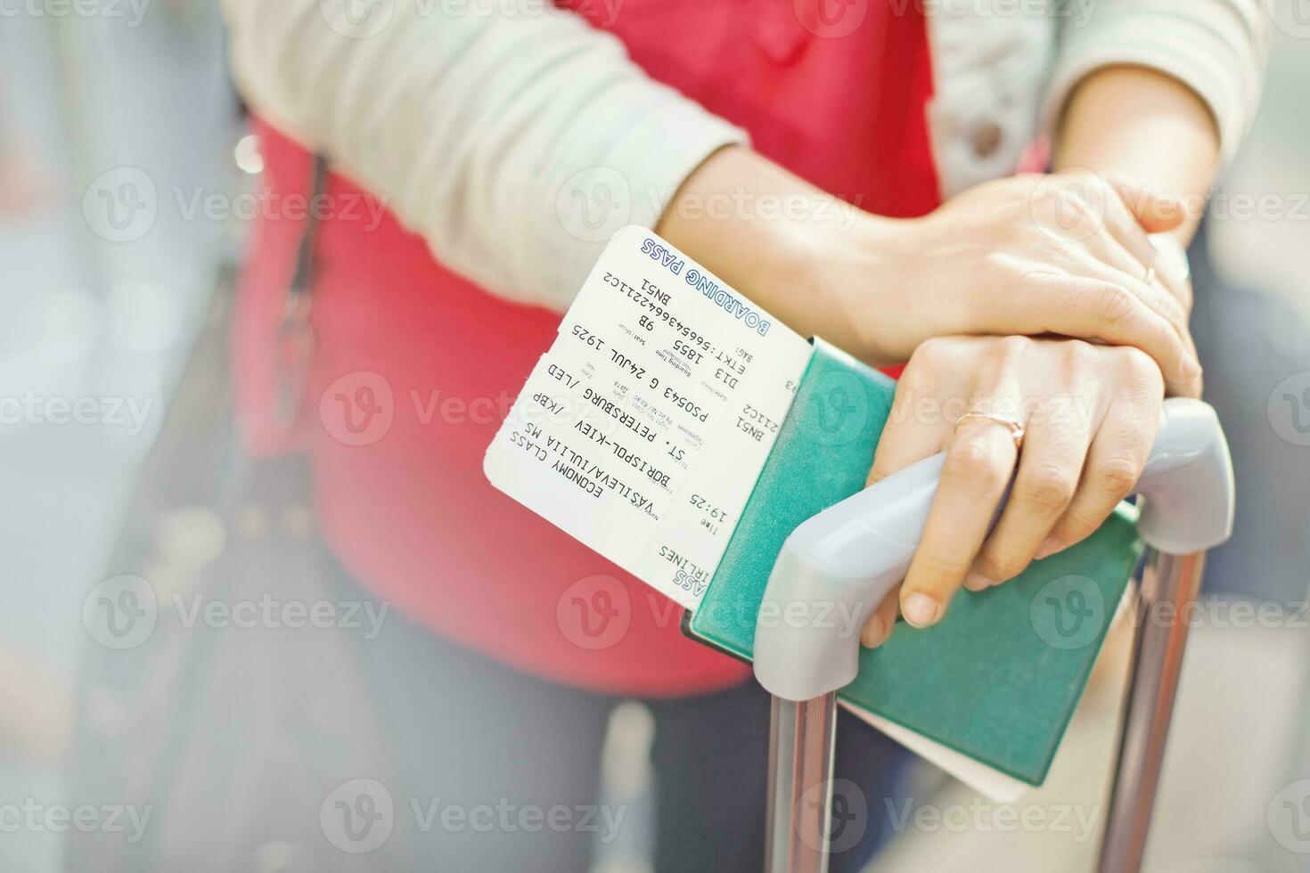 a woman holding a boarding pass and luggage photo