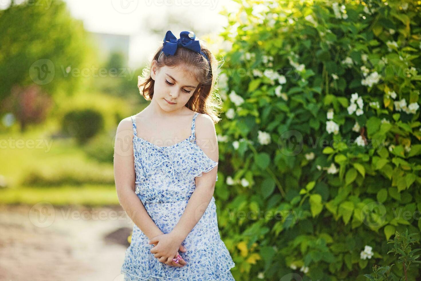 a little girl in a blue dress standing in the grass photo