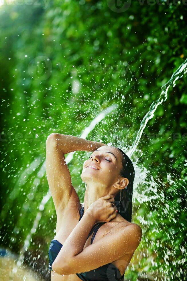 a woman in a bikini is splashing water on her head photo