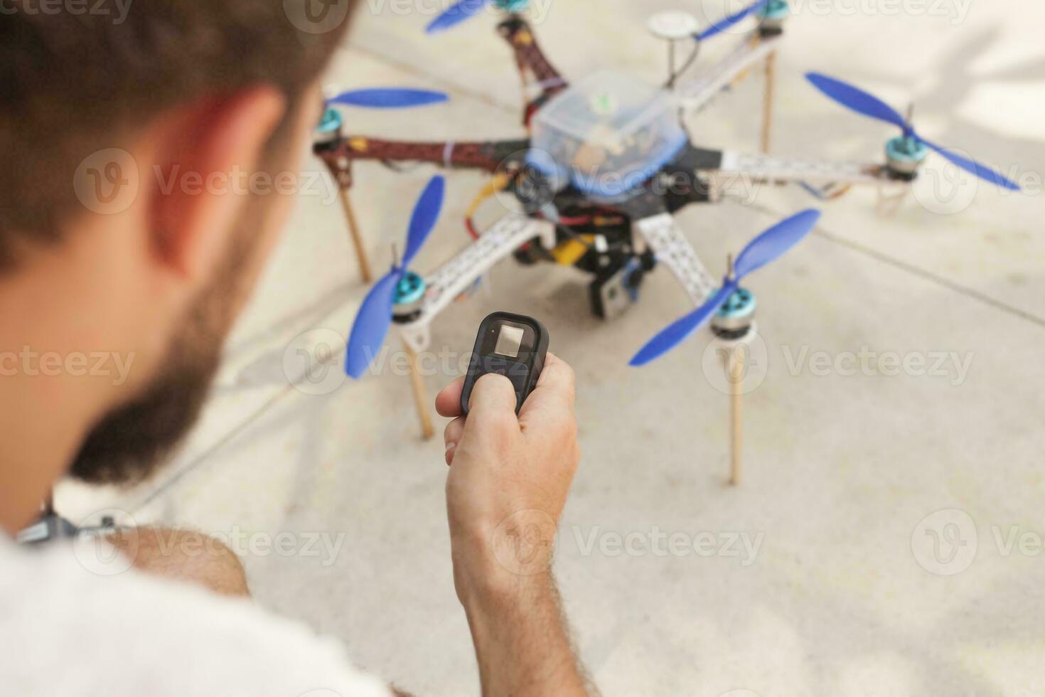 a man holding a remote control to a remote controlled drone photo
