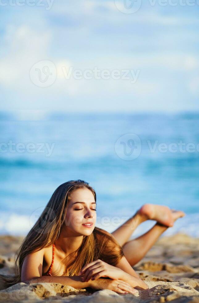 a woman laying on the beach with her feet in the sand photo