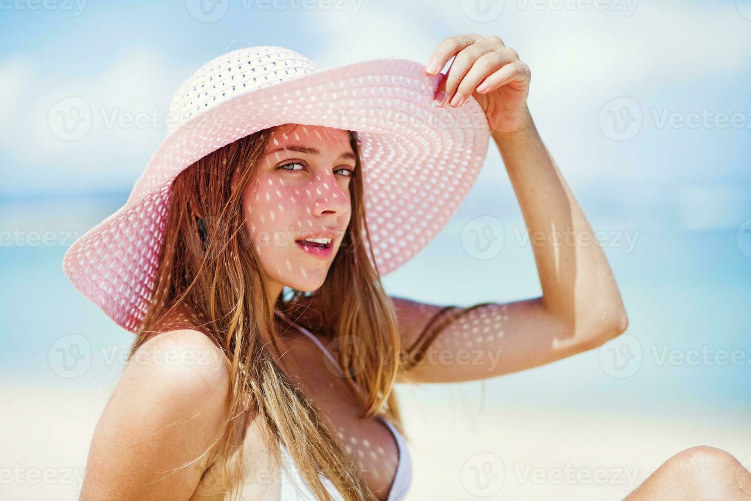 a woman in a pink hat on the beach photo