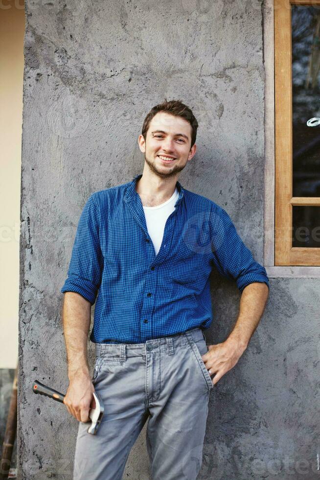 a man in a blue shirt and gray pants is standing in front of a building photo