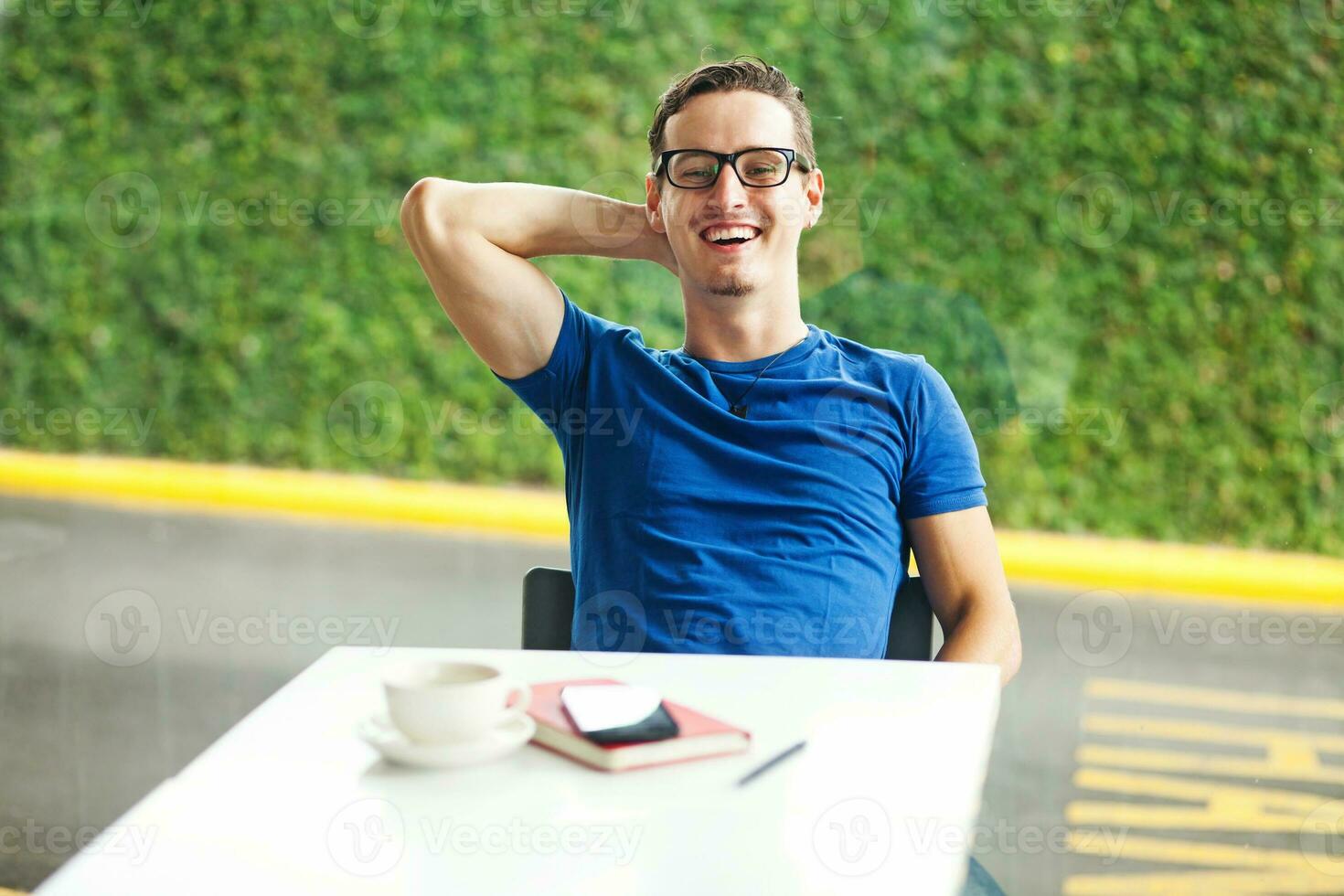 a man in glasses sitting at a table with a cup of coffee photo