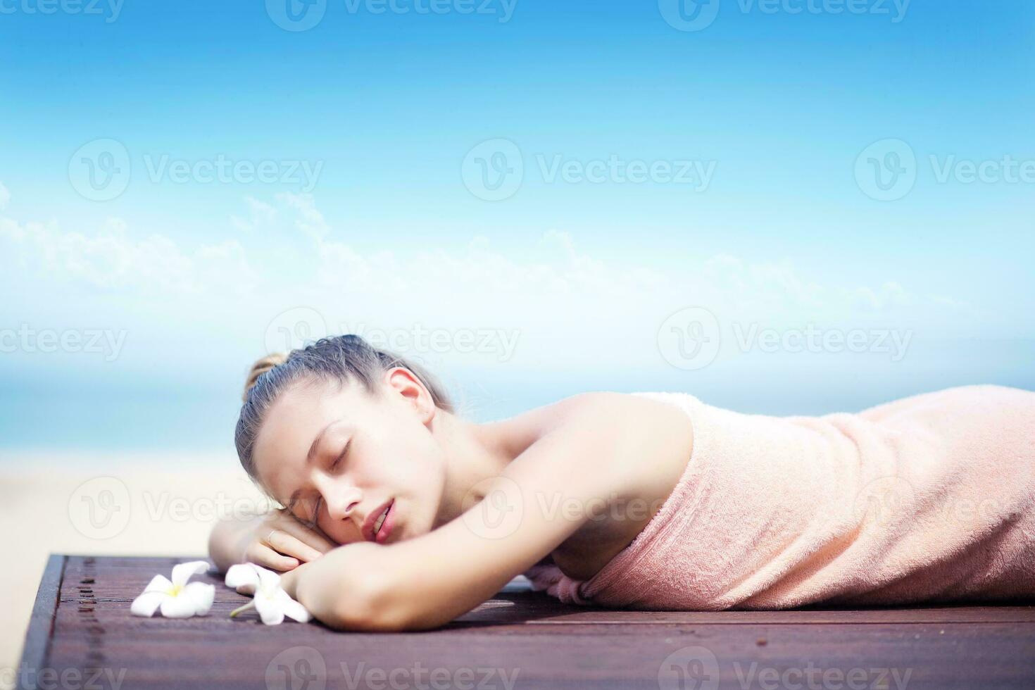 a woman in a towel laying on a wooden table with flowers photo