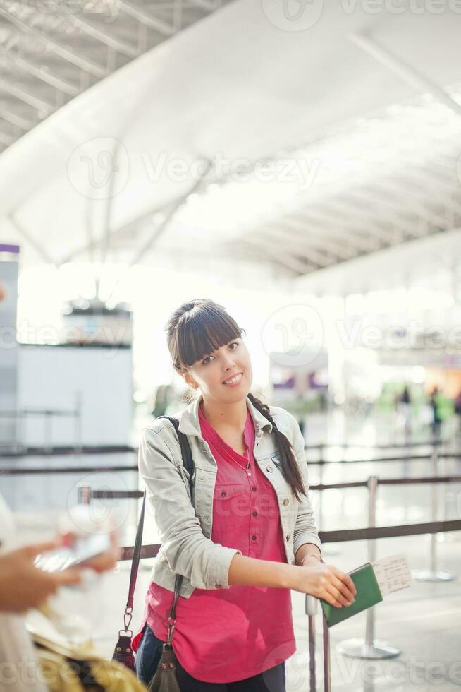 two women standing in an airport with luggage photo