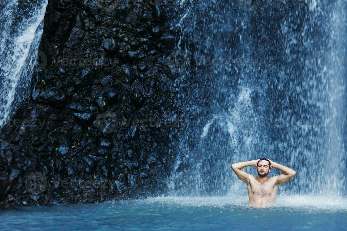 a man standing in front of a waterfall photo