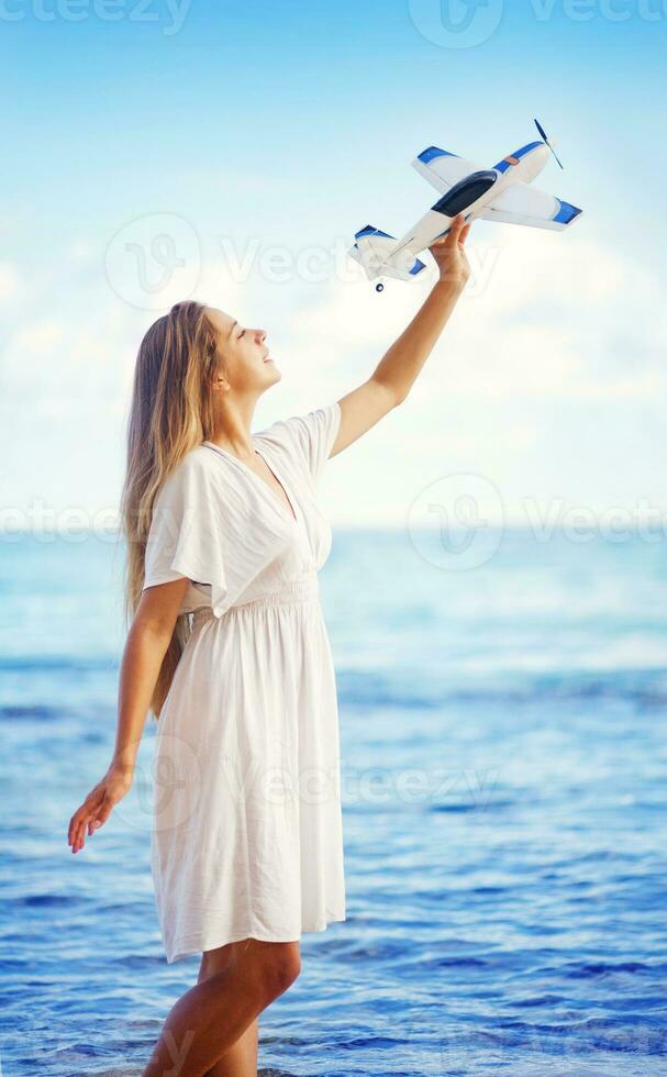 a woman in a white dress holding a toy airplane photo