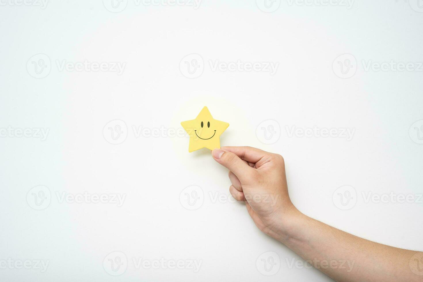 Hand holding yellow star happy smile face, good feedback rating and positive customer review,experience, satisfaction survey,mental health assessment, compliment. photo