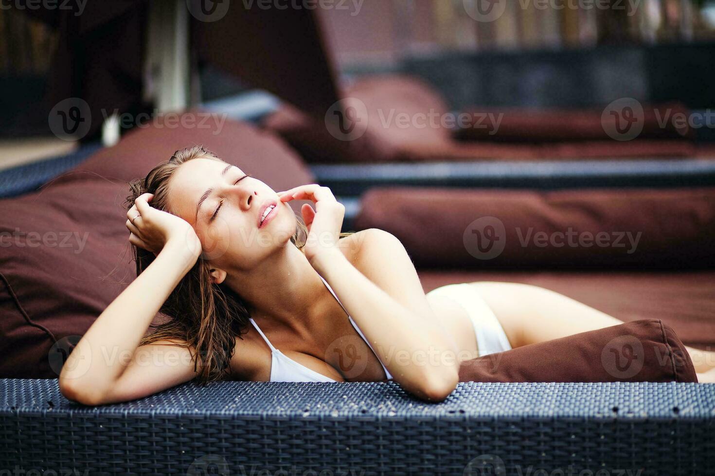 a woman in a white bikini laying on a couch photo