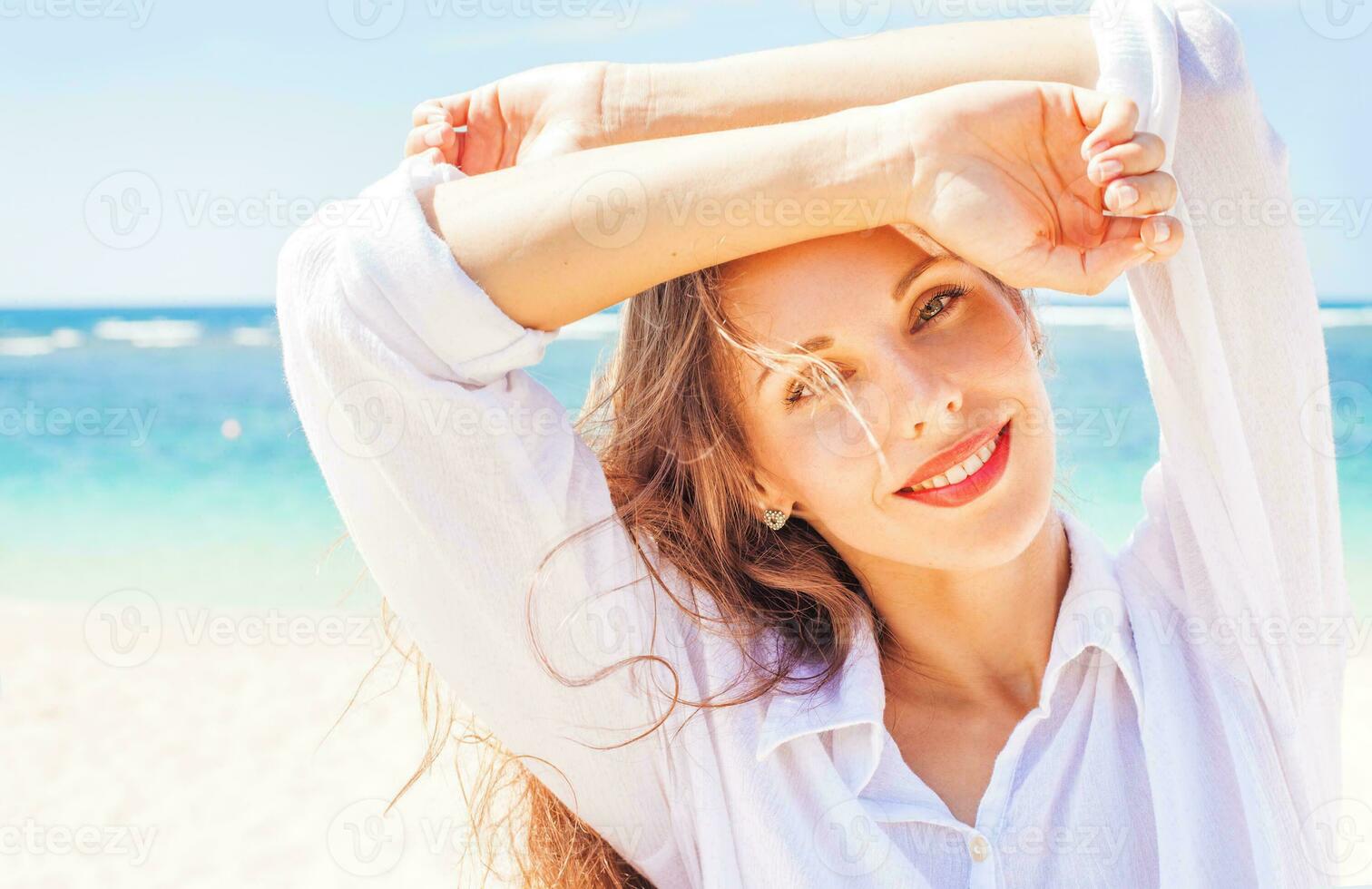 a woman posing on the beach with her arms up photo
