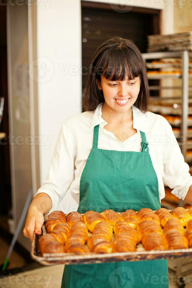 a woman holding a tray of baked goods photo