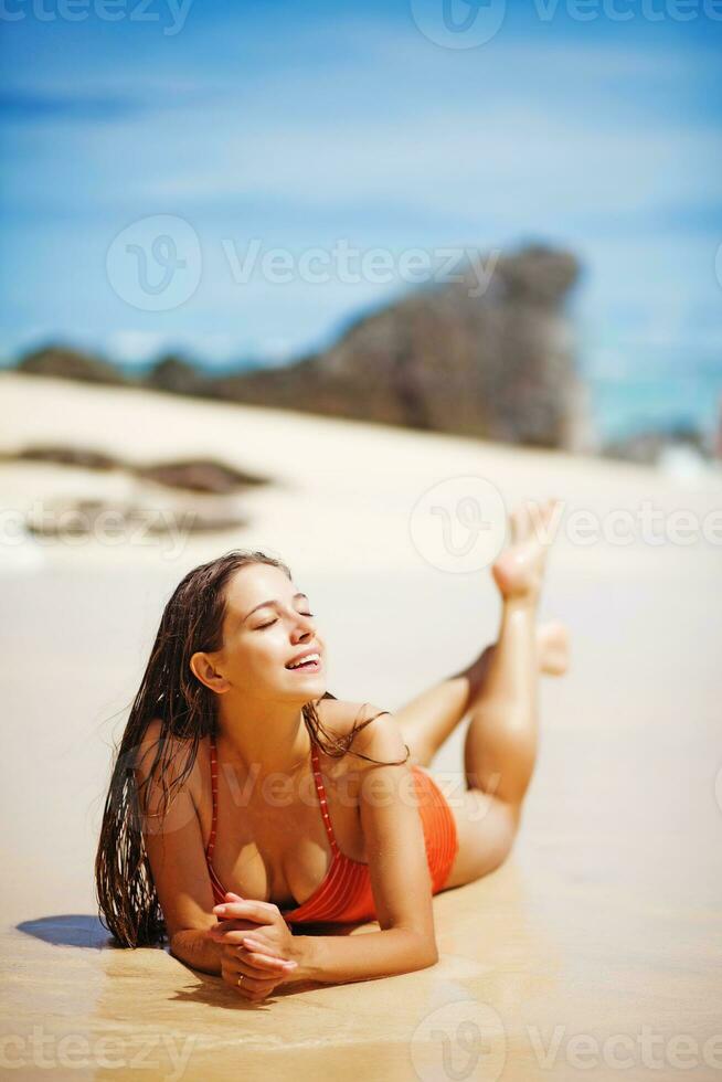 un mujer en un naranja traje de baño en pie en el playa foto