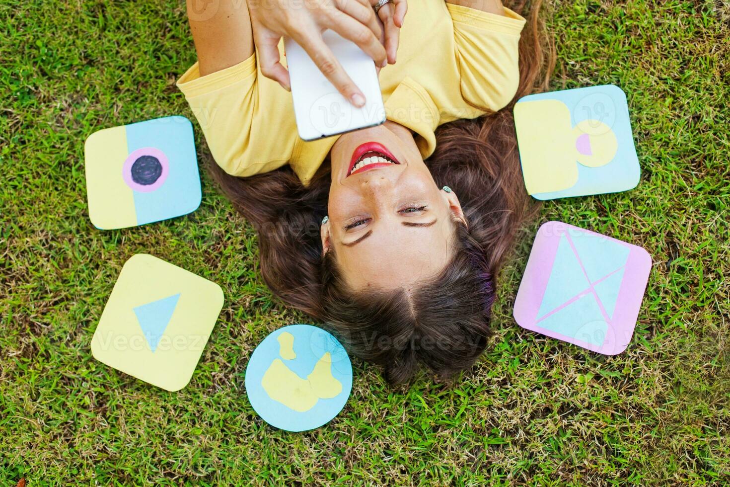 a woman laying on the grass with her phone and cards photo