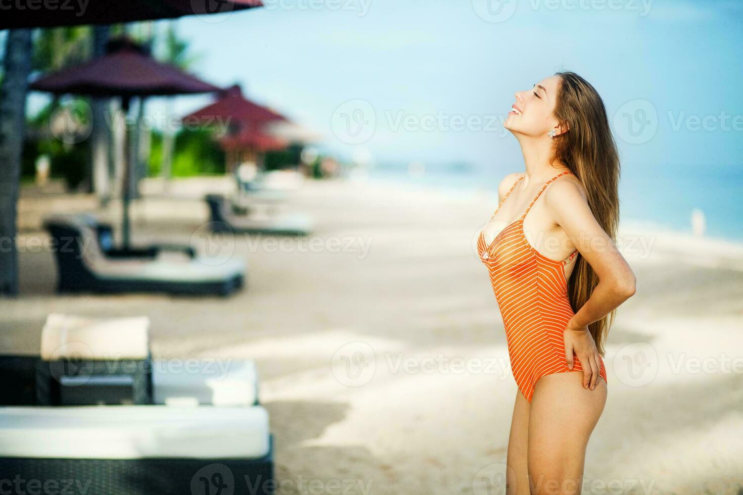 a woman in an orange swimsuit on the beach photo