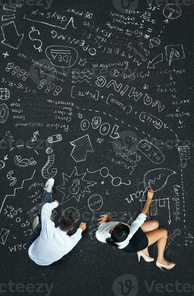 two people sitting on the ground with chalk drawings on the ground photo