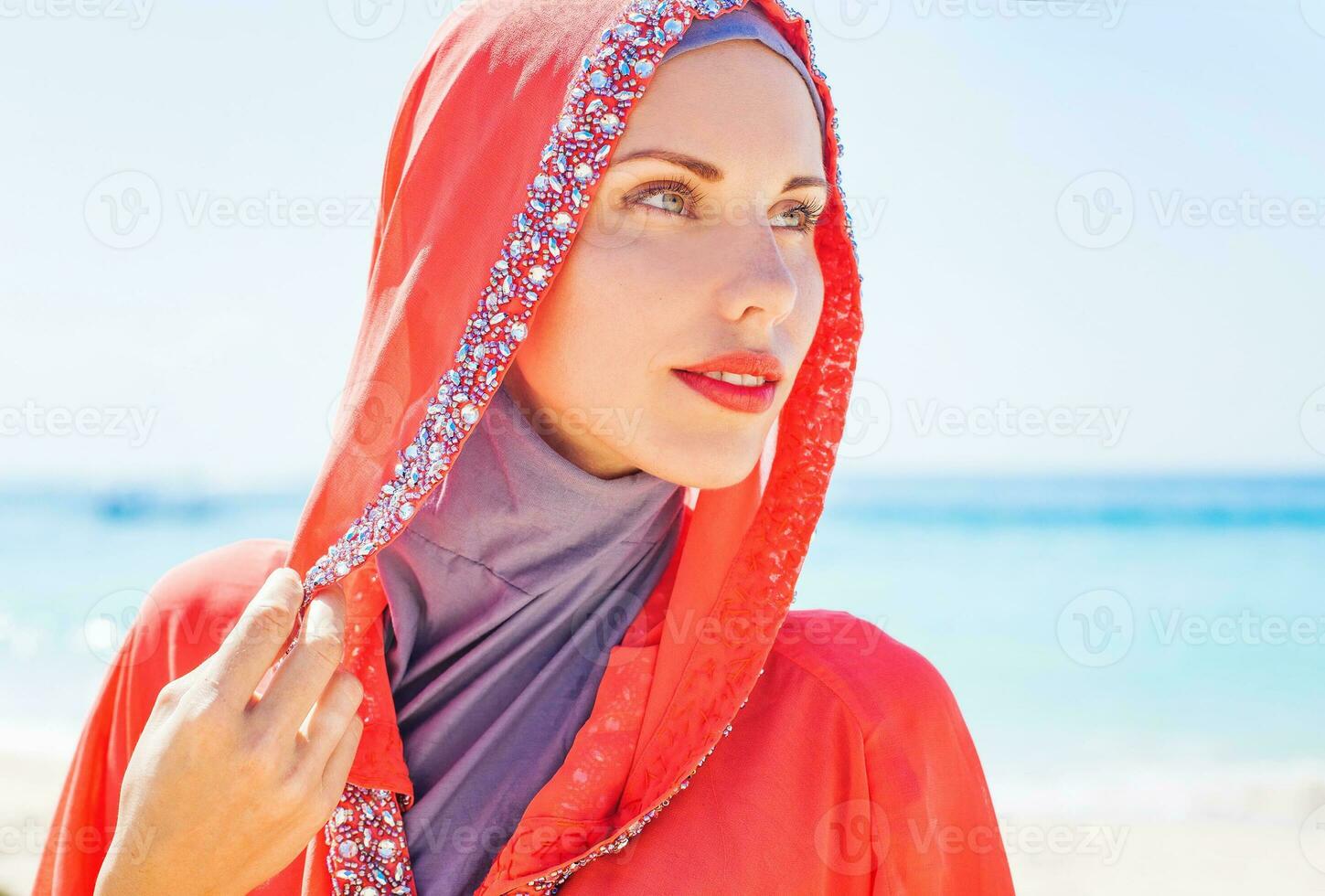 hermosa musulmán caucásico ruso mujer vistiendo rojo vestir relajante en un playa foto