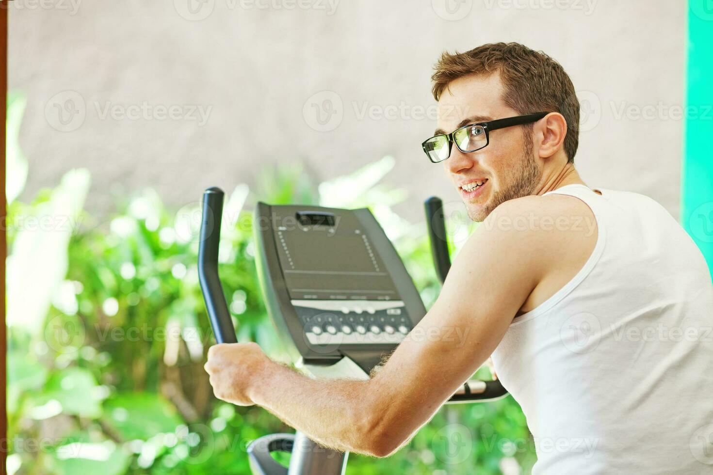 a man in glasses is riding an exercise bike photo