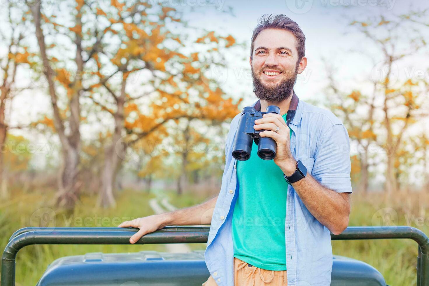 a man with a beard and a green shirt is holding binoculars photo