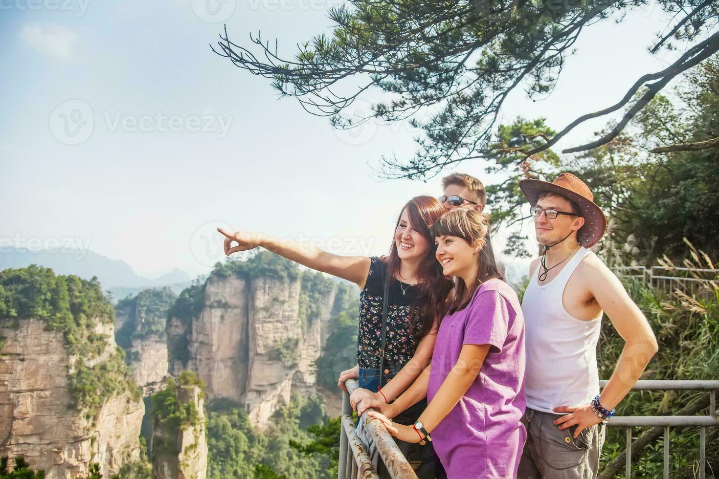 four people standing on a railing overlooking the mountains photo