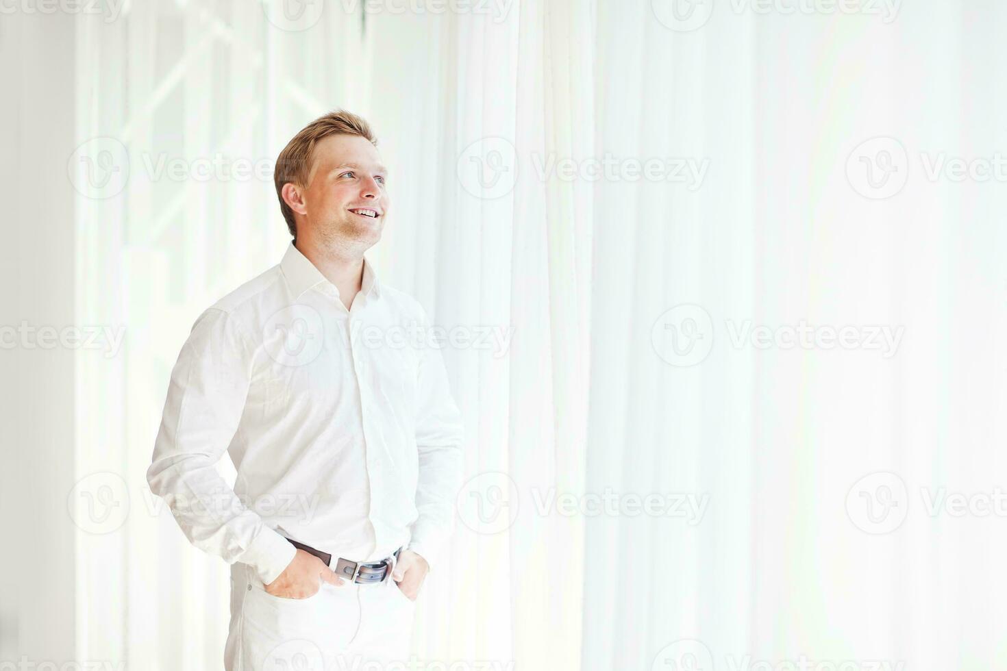 a man is adjusting his shirt in front of a window photo