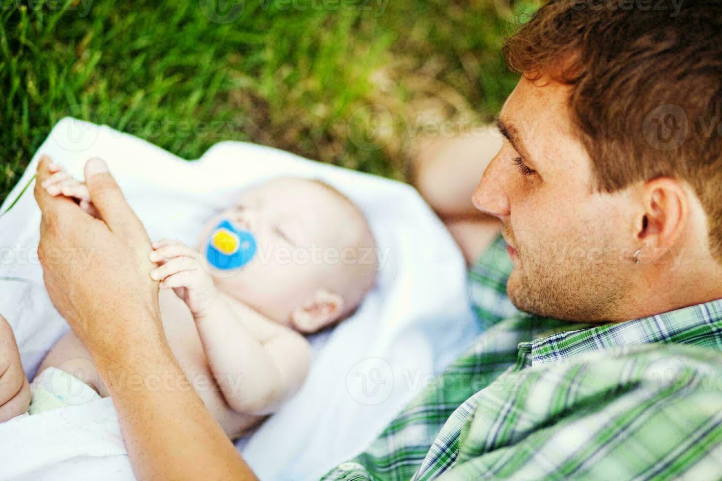 a man laying on the grass with a baby photo