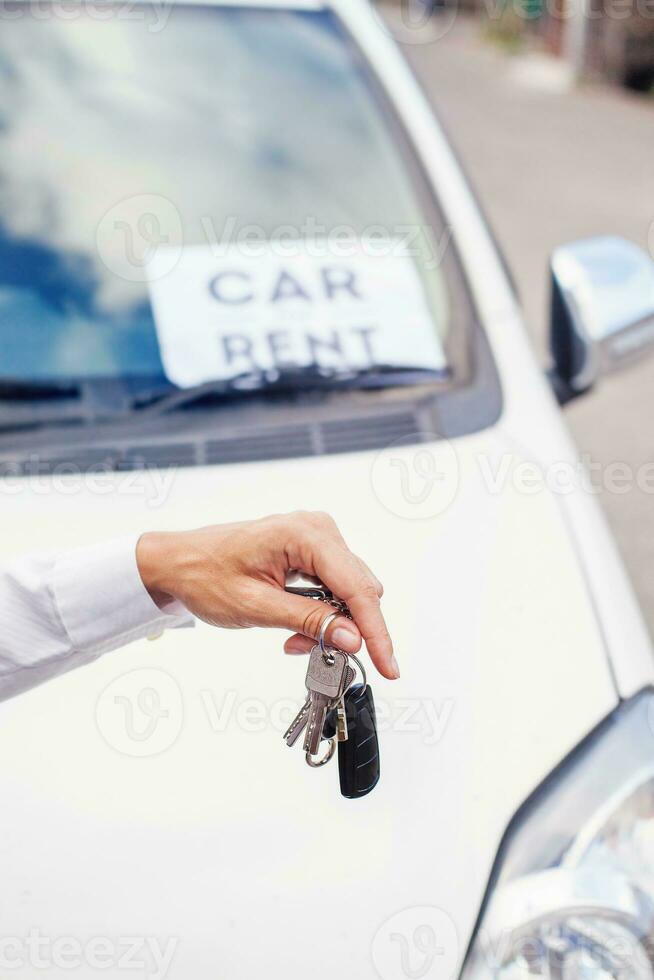 a person holding a car key and a car rental sign photo